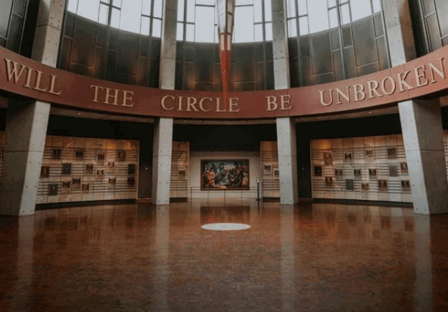 A photo of the Country Music Hall of Fame building in Nashville, featuring its striking modern architecture with sleek lines and expansive glass windows, set against a clear sky.
